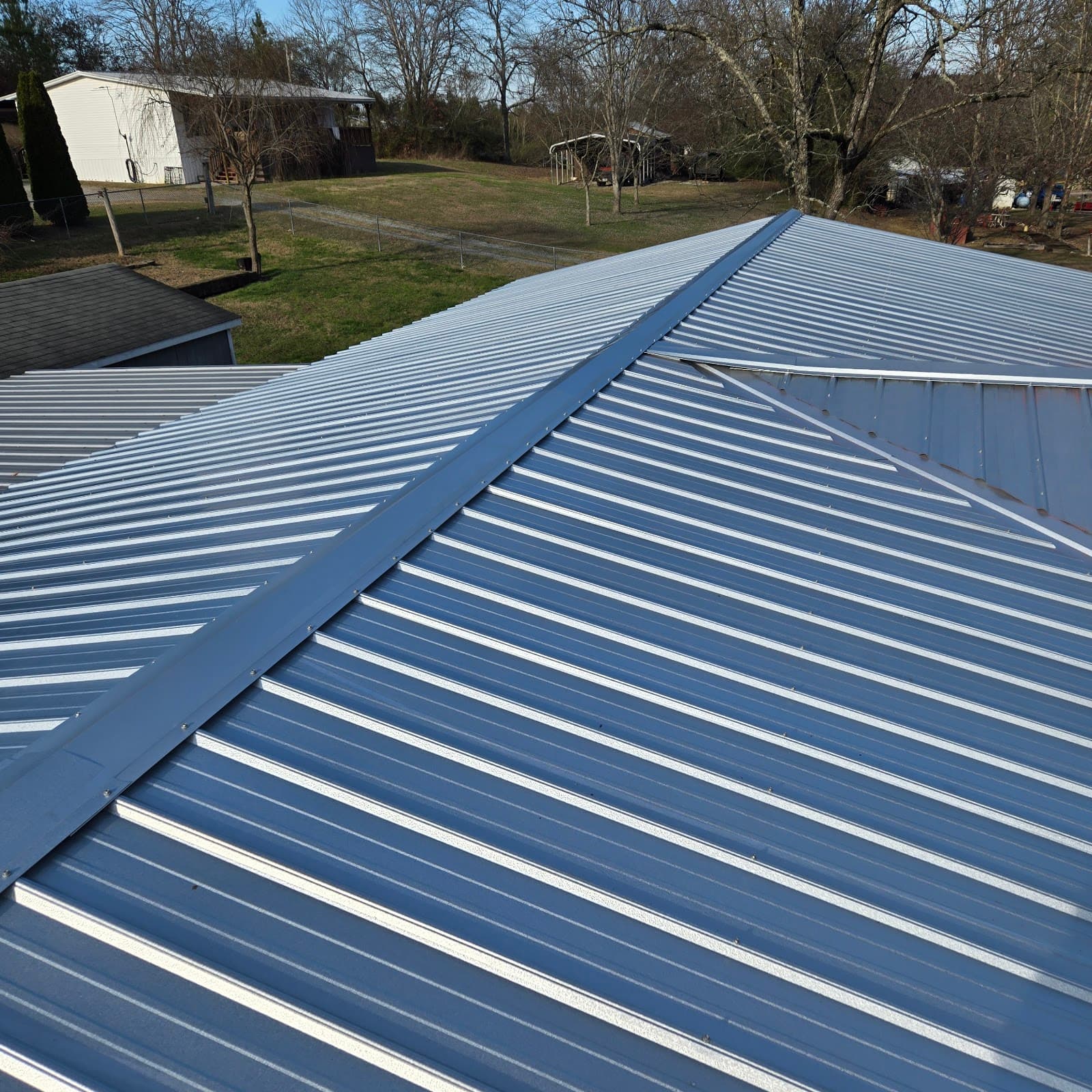 Freshly installed light grey metal roof panels with finished ridge cap