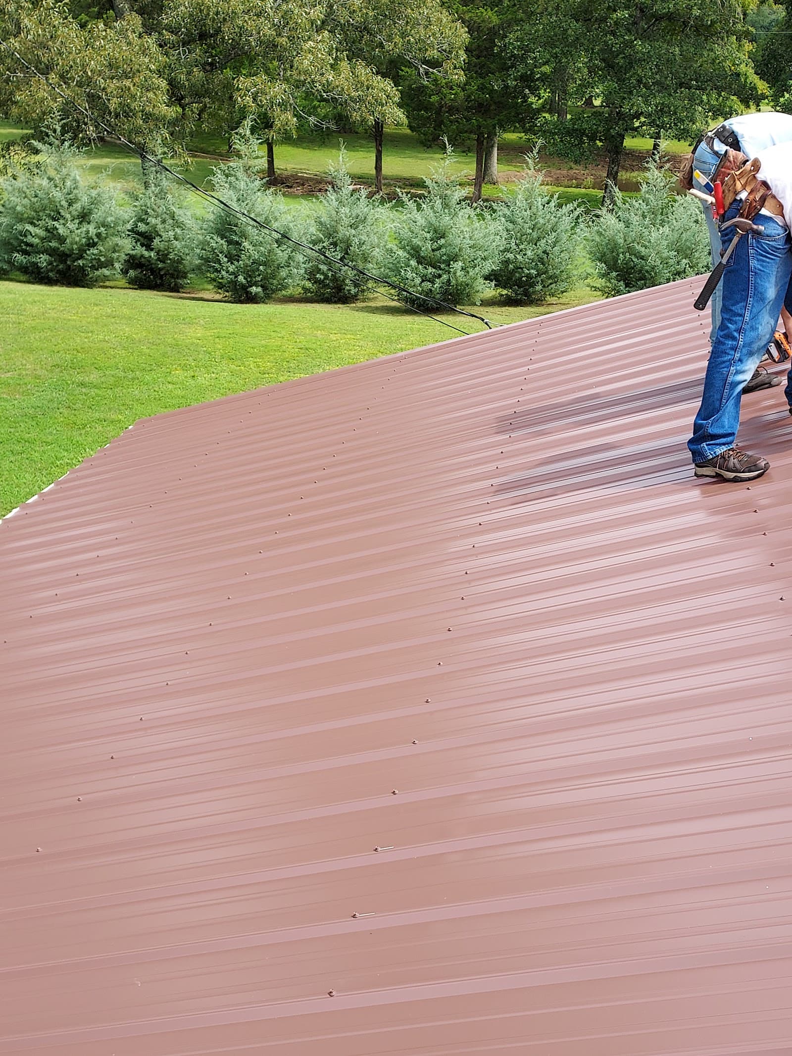 Roofer working on a newly fastened brown corrugated metal roof
