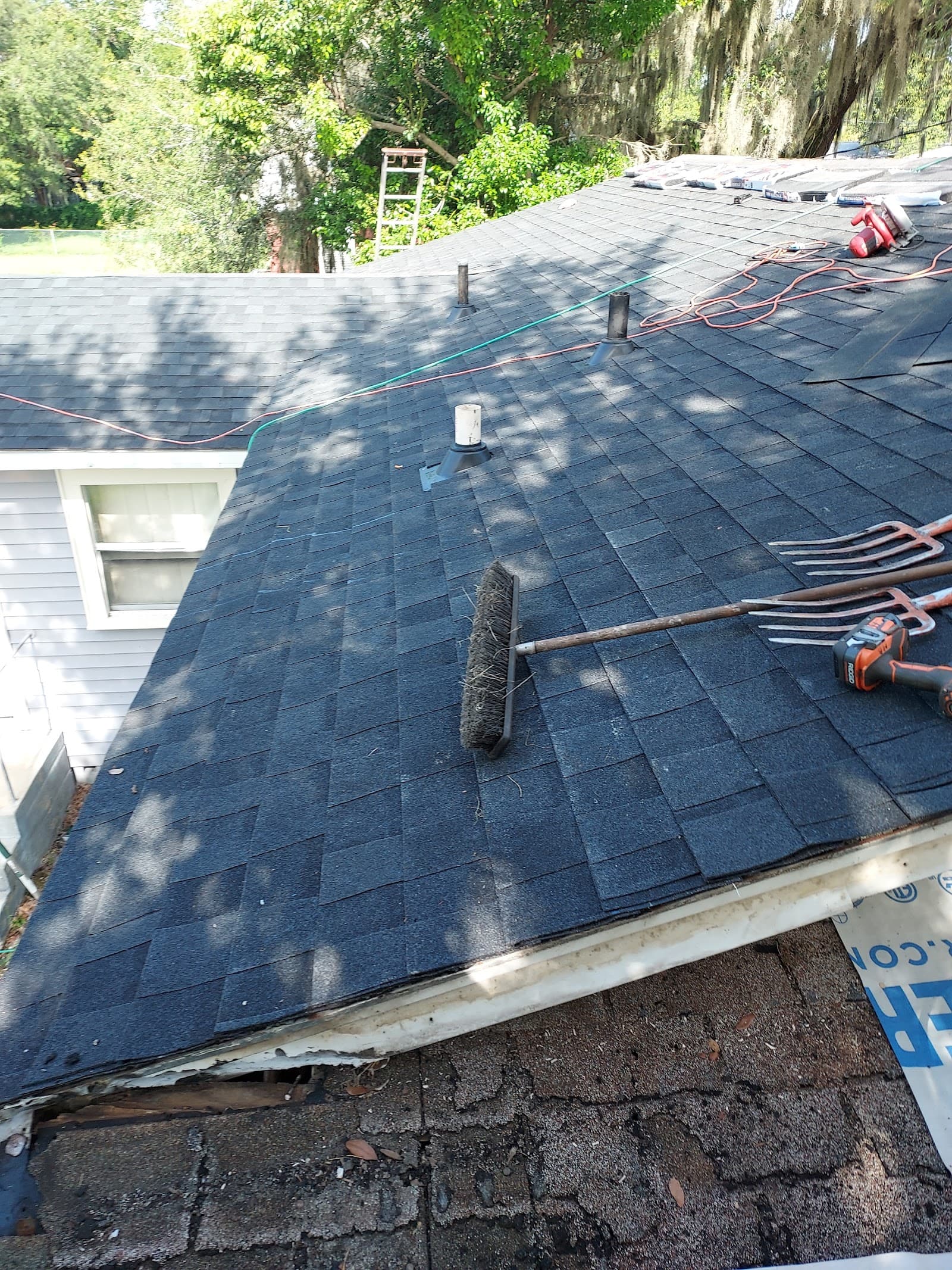 Stripped asphalt shingle roof being cleared and prepped with tools